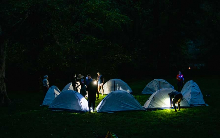 headlamps illuminate a campsite on an outward bound course